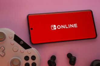 Dhaka, Bangladesh- 15 July 2025: Smartphone with nintendo online logo, game controller, and earbuds