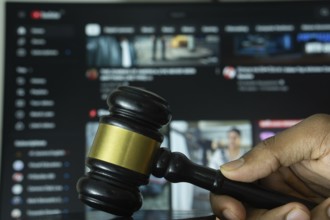 Dhaka, Bangladesh- 20 June 2025: A hand holds a gavel in front of a computer screen displaying