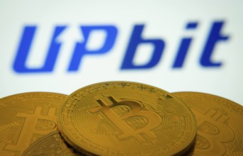 Dhaka, Bangladesh- 18 Sep 2025: Close-up of Bitcoin coins with thex Upbit logo visible on a screen