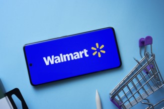 Dhaka, Bangladesh- 03 July 2025: Smartphone displaying Walmart logo with shopping cart on a blue