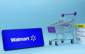 Dhaka, Bangladesh- 03 July 2025: Smartphone with Walmart logo next to a small shopping cart and