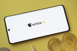 Dhaka, Bangladesh- 03 June 2025: whitebit logo on smartphone screen near Bitcoin coin and QR code