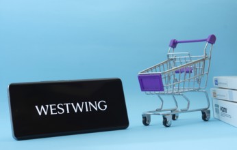 Dhaka, Bangladesh- 03 July 2025: Smartphone with Westwing logo next to a small shopping cart and