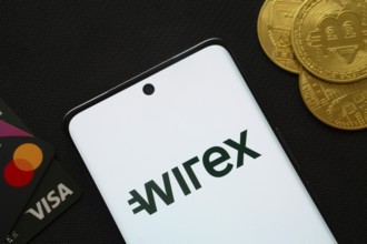 Dhaka, Bangladesh- 15 June 2025: Smartphone displaying wirex logo surrounded by Bitcoin coins and