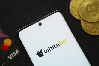 Dhaka, Bangladesh- 15 June 2025: Smartphone displaying whitebit logo surrounded by Bitcoin coins