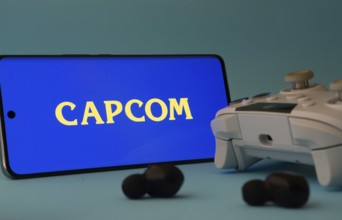 Dhaka, Bangladesh- 19 Sep 2025: A smartphone with a Capcom icon next to a controller and earbuds on