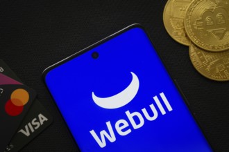 Dhaka, Bangladesh- 26 Aug 2025: Smartphone displaying webull logo surrounded by Bitcoin coins and