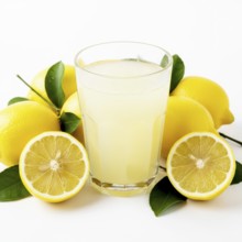 A vibrant image showcasing a glass of freshly squeezed lemonade surrounded by ripe lemons and green
