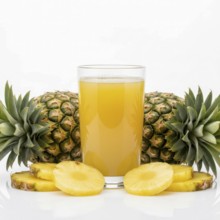 A refreshing glass of pineapple juice is surrounded by whole pineapples and sliced pieces, perfect
