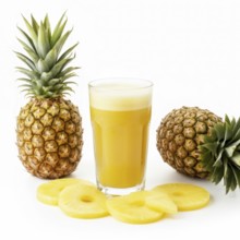 A vibrant image showcasing a glass of freshly squeezed pineapple juice alongside whole pineapples