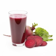 A refreshing glass of vibrant red beetroot juice is presented alongside sliced and whole beets,