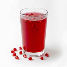 A vibrant image showcasing a glass of fresh pomegranate juice, garnished with seeds, set against a