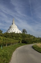 White pagoda surrounded by green nature and meadows under a blue sky, Stupa am Wagram Grafenwörth