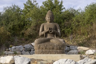 Sitting Buddha statue surrounded by stones and vegetation, Stupa am Wagram Grafenwörth Weinviertel