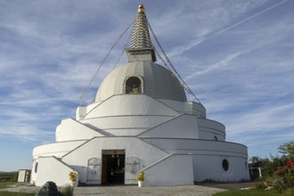 White stupa with an entrance under a clear blue sky, peaceful atmosphere, Stupa am Wagram