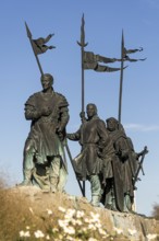 Bronze warrior statues with flags, conveying a historic and majestic feeling, stand against a blue