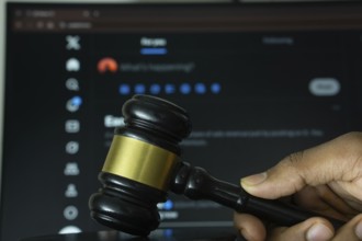 Dhaka, Bangladesh- 20 June 2025: A hand holds a gavel in front of a computer screen displaying X