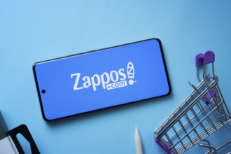 Dhaka, Bangladesh- 03 July 2025: Smartphone displaying Zappos logo with shopping cart on a blue