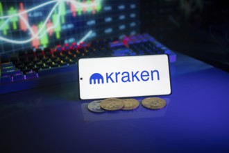 Bright Kraken logo on a phone with a vibrant trading screen and coins in view