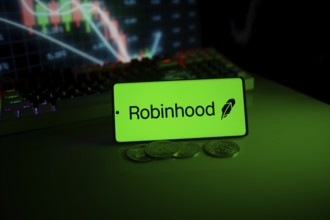 Robinhood logo on a phone with coins, set against a stock chart with green neon glow