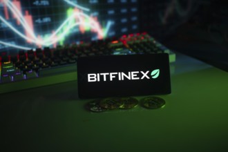 Bitfinex screen with coins in front of a stock chart illuminated by green neon lights
