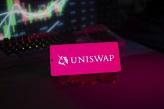 Uniswap logo on smartphone with coins and stock chart, highlighting digital finance and trading