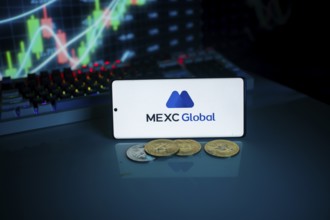 Phone showing MEXC Global logo, coins, and market data, highlighting cryptocurrency trading