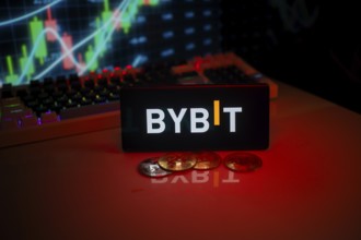 BYBIT logo on phone with a red glow, coins, and stock chart, suggesting a trading focus