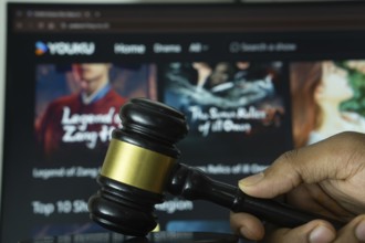 Dhaka, Bangladesh- 20 June 2025: A hand holds a gavel in front of a computer screen displaying