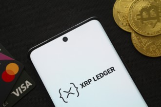 Dhaka, Bangladesh- 26 Aug 2025: Smartphone displaying XRP Ledger logo surrounded by Bitcoin coins