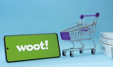 Dhaka, Bangladesh- 03 July 2025: Smartphone with Woot logo next to a small shopping cart and boxes