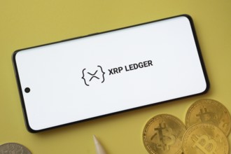 Dhaka, Bangladesh- 26 Aug 2025: XRP Ledger logo on smartphone screen near Bitcoin coin and QR code