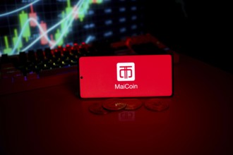 MaiCoin logo displayed on a red screen with coins and trading graphs in the background