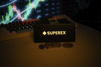 SUPEREEX logo on a smartphone with coins and financial display in the background