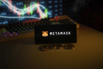 Phone features MetaMask logo with crypto coins and brightly lit trading screen