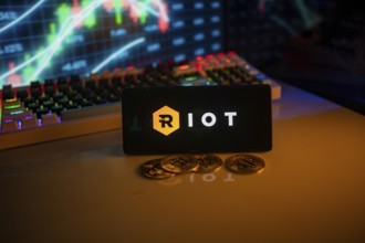 RIOT app on phone screen with coins and stock graph backdrop