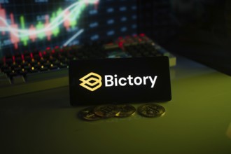 Bictory logo on a screen with coins and a vibrant chart in a dark environment