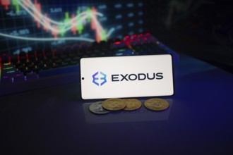 Exodus logo on a smartphone amid digital currencies and trading market charts