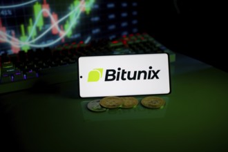 Bitunix logo on a phone with cryptocurrencies and market trend charts in the background