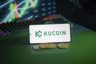 KuCoin logo on smartphone with coins, green neon lights, and trading charts in background