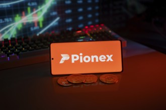 Pionex logo on smartphone with coins, orange neon lights, and trading charts in background