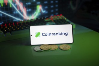 Coinranking logo on smartphone with coins, green neon lights, and trading charts in background