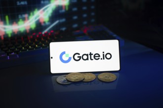 Gate.io logo on smartphone with coins, neon lights, and trading charts in background