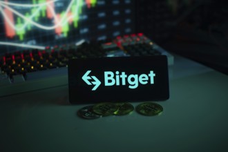 Bitget logo on black screen with coins and trading graphs in the background