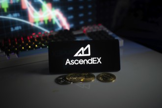 AscendEX logo with cryptocurrency coins on a desk, trading graphs in background