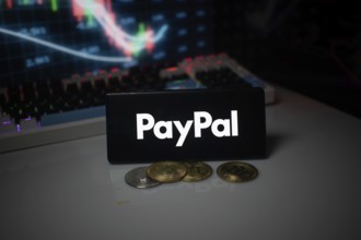 PayPal logo shown with coins and illuminated market analysis graph