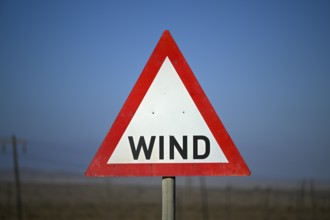 Caution wind sign on a road near Oranjemund, diamond restricted area, Karas region, Namibia