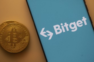 Bitget logo on a blue smartphone screen next to a Bitcoin on an orange backdrop