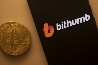 Smartphone displaying Bithumb logo with a Bitcoin on an orange background