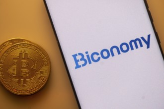 Bitcoin next to a smartphone showing the Biconomy logo against an orange backdrop
